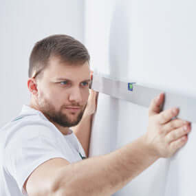 Man with level installing wall storage  | Serious Garages