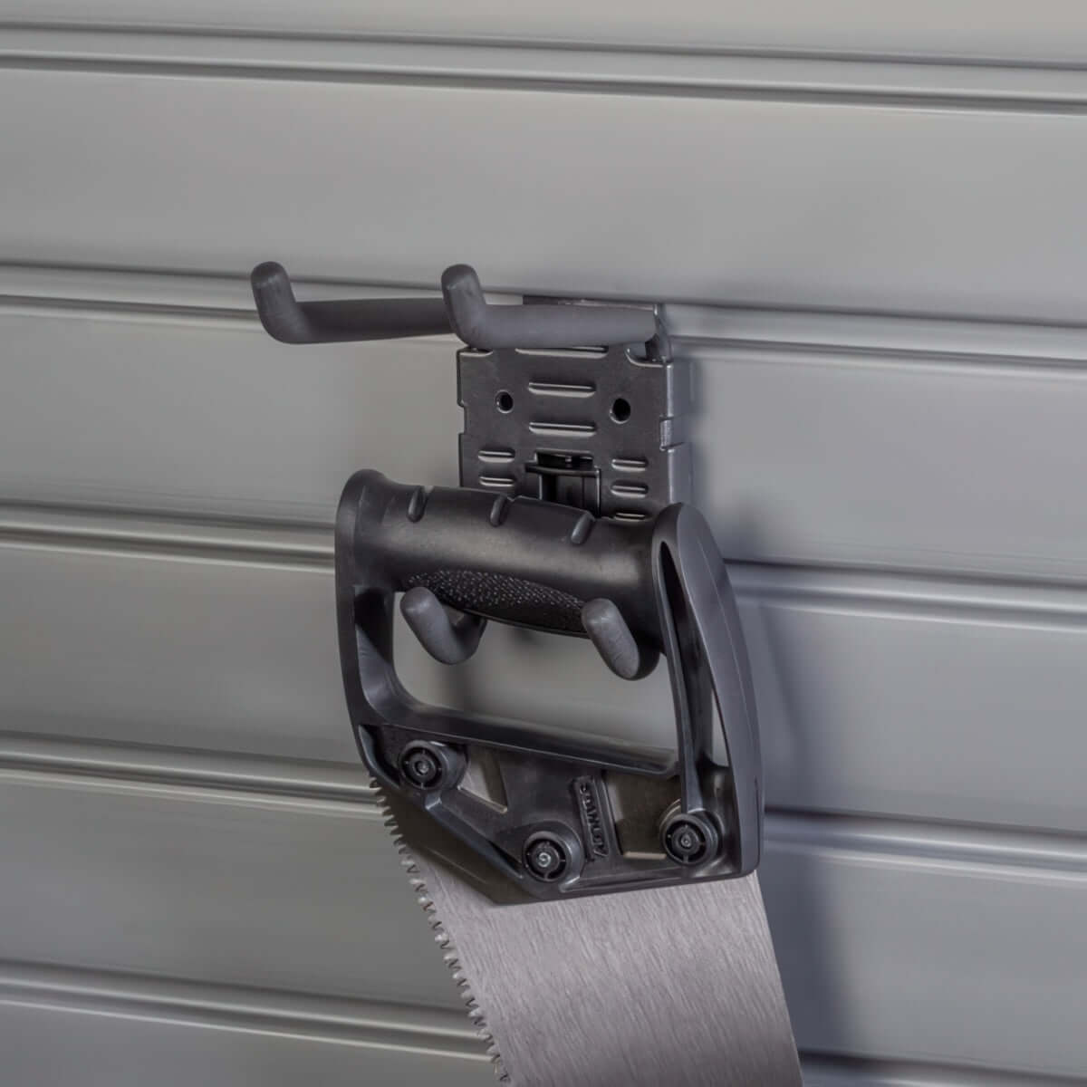 Slatwall Hooks double utility hook mounted on gray slatwall panel securely holding a handsaw by its handle